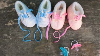 Blue and pink baby shoes with 2019 written in the laces and blue and pink pacifiers