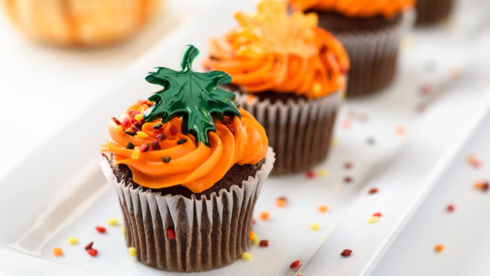 Chocolate cupcakes with orange frosting and leaf decoration and sprinkles