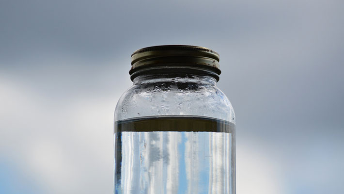 A jar of moonshine held up against the sky