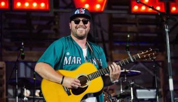 Mitchell Tenpenny smiling on stage playing guitar
