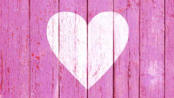 Old wooden board background with cracked pink paint and white heart shape