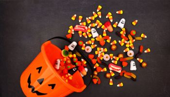 Halloween Jack o Lantern pail with spilling candy, above view on a dark background