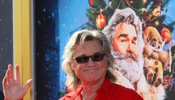 Kurt Russell waves in front of Christmas Chronicles poster