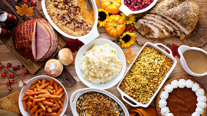 Thanksgiving table with roasted turkey, sliced ham and side dishes