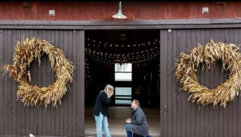 A couple getting engaged in front of a barn