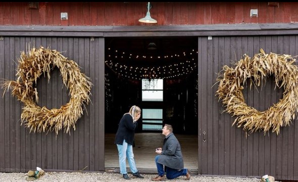 A couple getting engaged in front of a barn