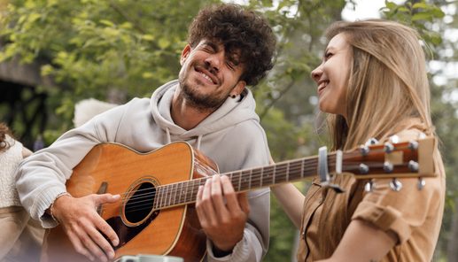 Carefree man playing a guitar to his friends in nature.
