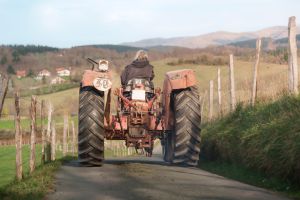 Woman farmer driving tractor on country road near farm in rural landscape