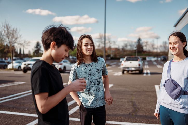 Group of smiling teenagers hanging out in shopping mall parking lot
