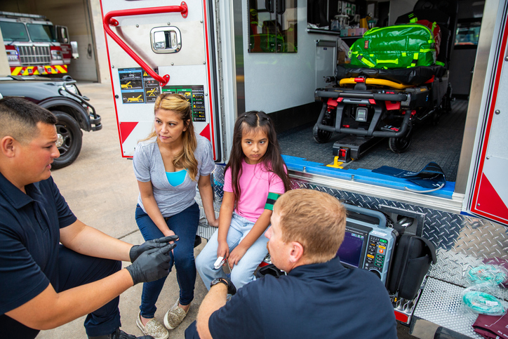 mother and daugther sitting on the back of an ambulance recieving treatment at the scene
